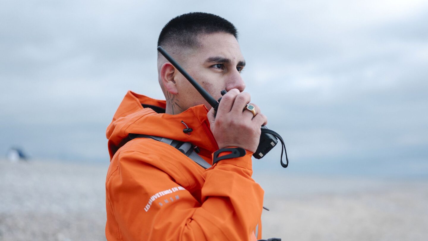 Nageur sauveteur de profil sur une plage parlant à la VHF